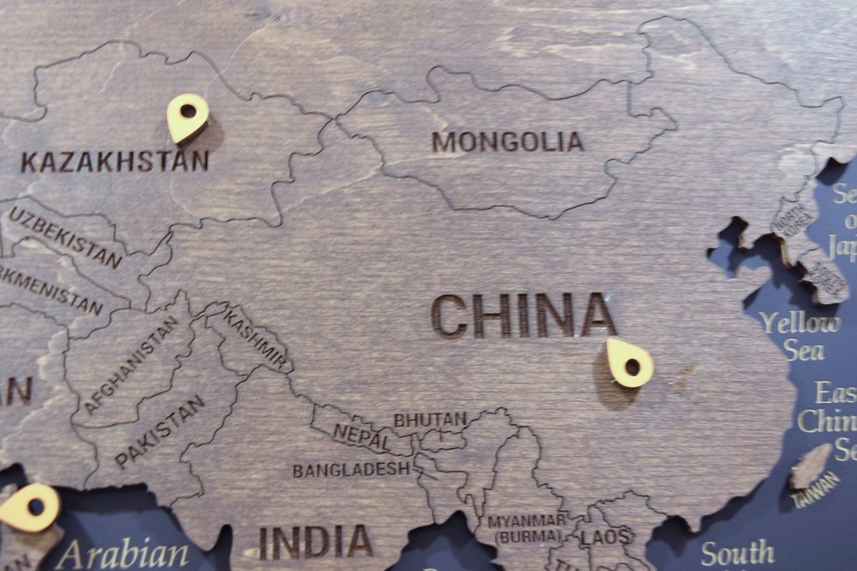 Wooden world map with client pins across Asia